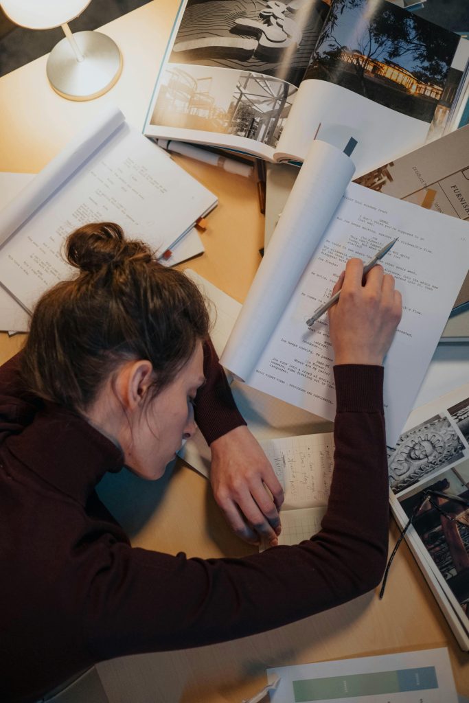 A woman sleeping on a desk surrounded by papers, illustrating stress and overwork.